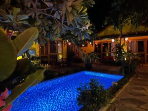 uma piscina com luzes azuis num quintal à noite em La Belle Anbang Homestay em Hoi An