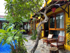 um edifício amarelo com cadeiras e uma árvore em frente em La Belle Anbang Homestay em Hoi An