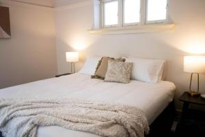 1 dormitorio con 1 cama blanca con almohadas y 2 lámparas en • Parkside • Spacious central family retreat en Alfredton