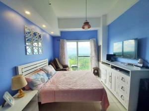 a bedroom with a bed and a desk and a television at Sofias Place w/ Massagechair in Tagaytay