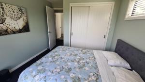 a bedroom with a bed with a floral blanket on it at Room With A view in Napier