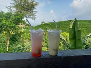 two drinks sitting on a ledge with a green field at Feby's Homestay in Ekas