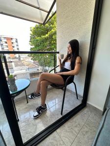 une femme assise sur une chaise avec une tasse de café dans l'établissement Hermoso ApartaEstudio Centrico, à Cartago