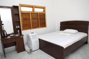 a bedroom with a bed with a desk and a window at Birunthavanam in Vavuniya