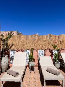 2 Betten auf einer Terrasse mit Topfpflanzen in der Unterkunft Riad Azad & Spa in Marrakesch