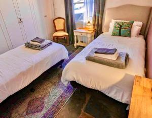 two beds in a room with a chair and a table at Inglenook Cottage in Moonta