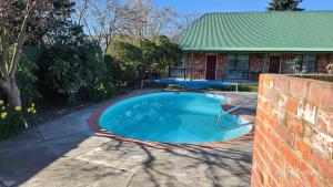 a swimming pool in front of a house at Ashburton's Regency Motel in Ashburton
