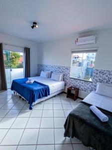 a bedroom with two beds and a window at Pousada Jardins - Mar Grande in Vera Cruz de Itaparica