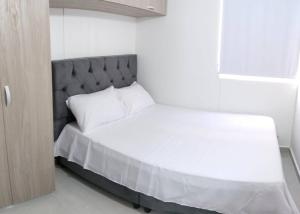 a bedroom with a white bed with a gray headboard at Encantador Apto Con Aire in Neiva