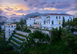 un bâtiment sur une colline avec des montagnes en arrière-plan dans l'établissement Silk Path Grand Sapa Resort & Spa, à Sa Pa