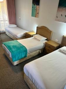 a hotel room with two beds and two tables at Acacia Rose Motor Inn in Barham