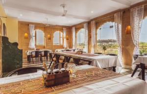 un comedor con mesas, sillas y ventanas en Hotel Meri Haveli, en Jaisalmer