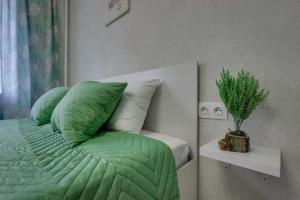 een bed met een groene dekbed en een plant ernaast bij Asaapart Mega Studio 2 in Alma-Ata