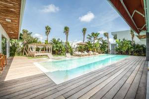 a swimming pool with a wooden deck and a house at Dreamy 5br Haven, 200m To Berawa's Blissful Beach in Canggu