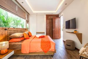 a bedroom with a bed with orange pillows and a television at Dreamy 5br Haven, 200m To Berawa's Blissful Beach in Canggu