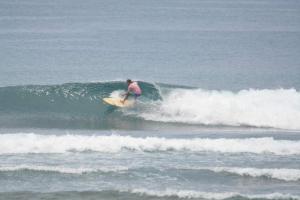 a man riding a wave on a surfboard in the ocean at Feby's Homestay in Ekas