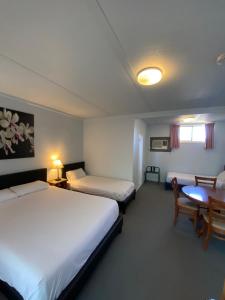 a hotel room with two beds and a table at Acacia Rose Motor Inn in Barham