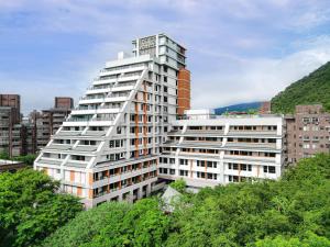 a tall white building with trees in front at Four Points by Sheraton Yilan Jiaoxi in Jiaoxi