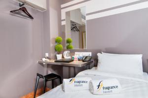 a bedroom with two beds and a desk with a mirror at Fragrance Hotel - Kovan in Singapore +14 photos