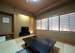 a living room with a table and a tv at Meitetsu Komaki Hotel in Komaki