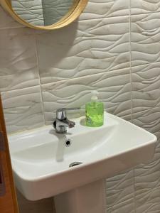 - un lavabo dans la salle de bains avec une bouteille de savon vert dans l'établissement Appartement Dahomey Bouznika, à Bouznika