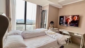 a bedroom with a bed and a tv on the wall at Condo with nearest to JIExpo 55” SMART TV (Netflix & Disney) and Wi-fi 50mb in Jakarta
