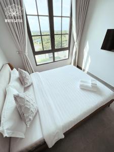 a bedroom with a large white bed with a window at White Lotus Hotel - Swanbay in Phước Lý
