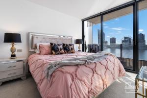 een slaapkamer met een roze bed en een groot raam bij Spectacular Victoria Harbour Apartment Docklands in Melbourne