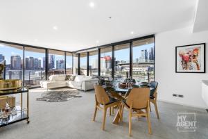 een woonkamer met een tafel en stoelen bij Spectacular Victoria Harbour Apartment Docklands in Melbourne