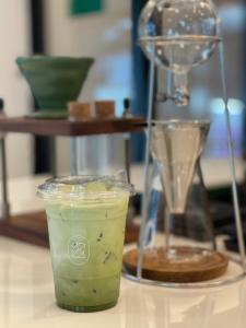 a green drink in a cup next to a blender at City Park Hotel Bangkok Pratunam by PCL in Bangkok