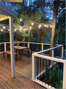 una terraza con banco, mesa y luces en Charming Country Retreat, en Hamilton