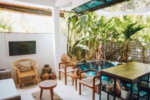 een patio met een tafel en stoelen en een zwembad bij Panayota House in Kuta Lombok