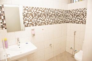ein weißes Badezimmer mit einem Waschbecken und einem Spiegel in der Unterkunft Nest and Nomad Homestay in Daressalam