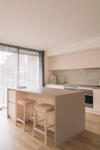 a kitchen with a large white island with two stools at Stadium View Townhouse in Geelong