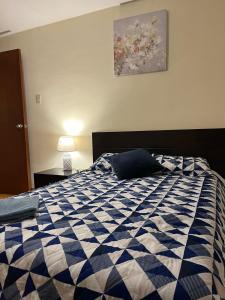 1 cama en un dormitorio con edredón azul y blanco en Departamento de 2 Habitaciones, full amoblada con todo para que disfrutes de tu Estancia en Cuenca