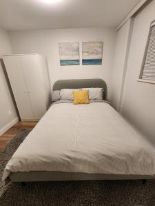 1 dormitorio con 1 cama grande con almohada amarilla en Charming East Van Hideaway - Near SkyTrain, en Vancouver