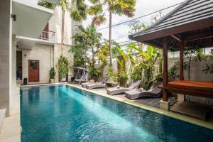 a swimming pool with chairs and a gazebo at Outpost Canggu in Canggu