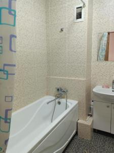 uma casa de banho com uma banheira branca e um lavatório. em Апартомент Алмалы напротив Алматы Арены em Almaty