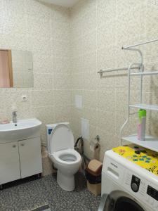 uma casa de banho com um WC, um lavatório e uma máquina de lavar roupa em Апартомент Алмалы напротив Алматы Арены em Almaty