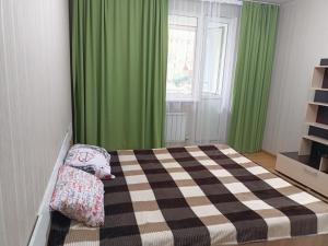um quarto com uma cama e cortinas verdes em Апартомент Алмалы напротив Алматы Арены em Almaty