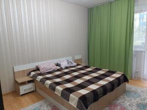 um quarto com uma cama e uma cortina verde em Апартомент Алмалы напротив Алматы Арены em Almaty