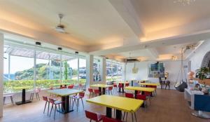 um restaurante com mesas, cadeiras e janelas em My Ocean Villa 月牙桐海景民宿 em Ruifang