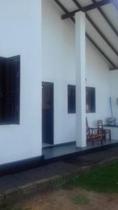 un edificio blanco con 2 mesas y 2 sillas en Induruwa Cottage en Induruwa