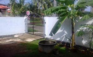 una cerca y un árbol con un cubo al lado en Induruwa Cottage en Induruwa