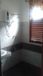 baño con lavabo y ventana con luz en Induruwa Cottage en Induruwa