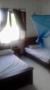 1 dormitorio con 2 camas y sombrilla azul en Induruwa Cottage en Induruwa