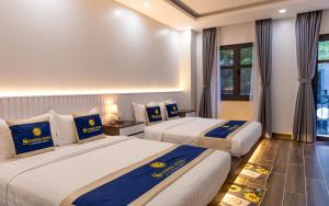 2 bedden in een hotelkamer met blauwe en gele kussens bij SUNRISE Hotel Bạc Liêu in Bạc Liêu