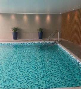 a large swimming pool with blue tiles in a building at Lindo Apartamento Alto Padrão Bela Cintra Stay in Sao Paulo