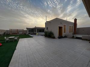 Casa con patio con mesa y sillas en شاليه وردة الدرة, en Unaizah