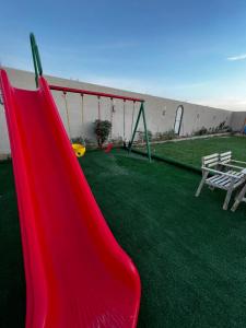 um parque infantil com um escorrega e um baloiço em شاليه وردة الدرة em Unayzah